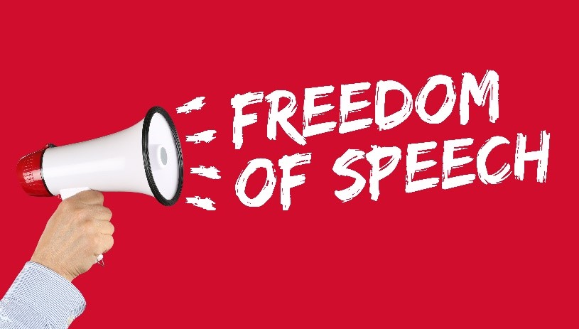 Hand held megaphone shouting “FREEDOM OF SPEECH” over a red background.
