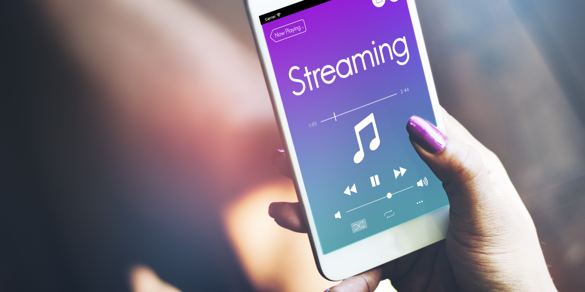 Hand holding a smart phone displaying the word “Streaming” above a musical note