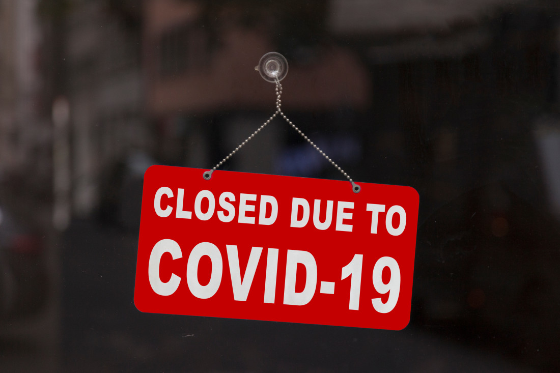 Red store sign saying “CLOSED DUE TO COVID-19”