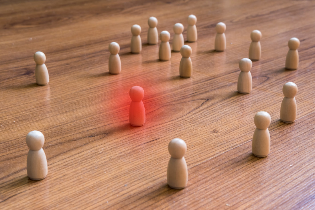 Pawns on a tabletop demonstrating social distancing with one highlighted in red